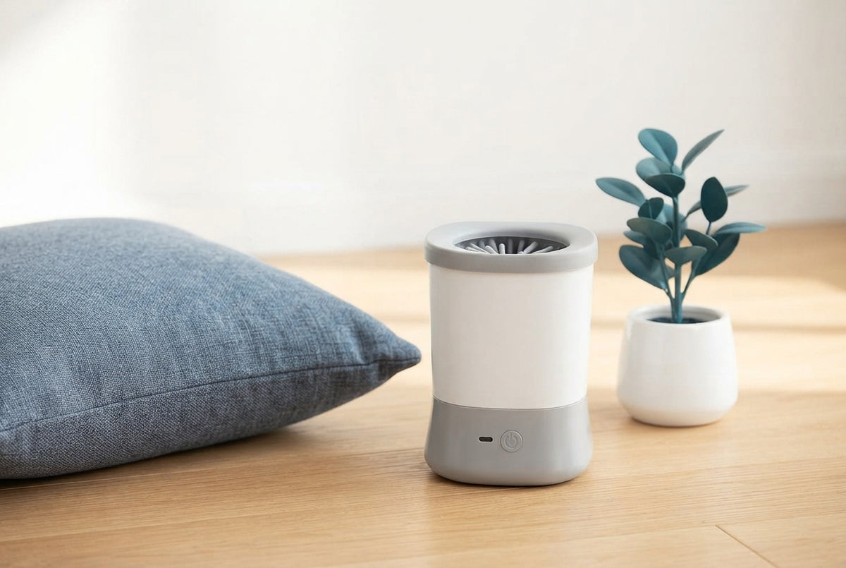 An electric pet paw cleaner sitting on a wooden floor next to a slate blue cushion in a bright, modern room.